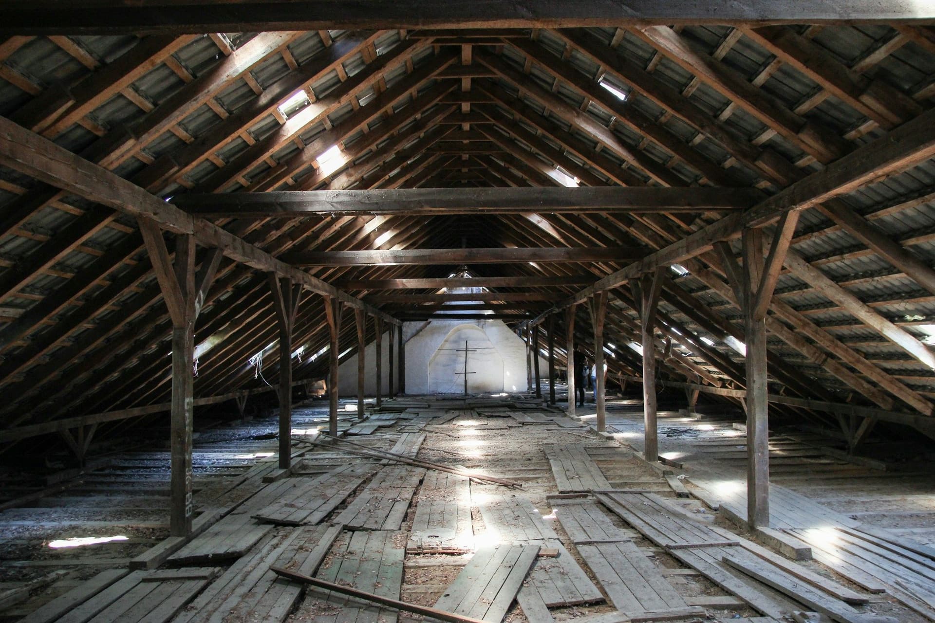 Large timber-framed attic with a boarded floor and light coming through the roof