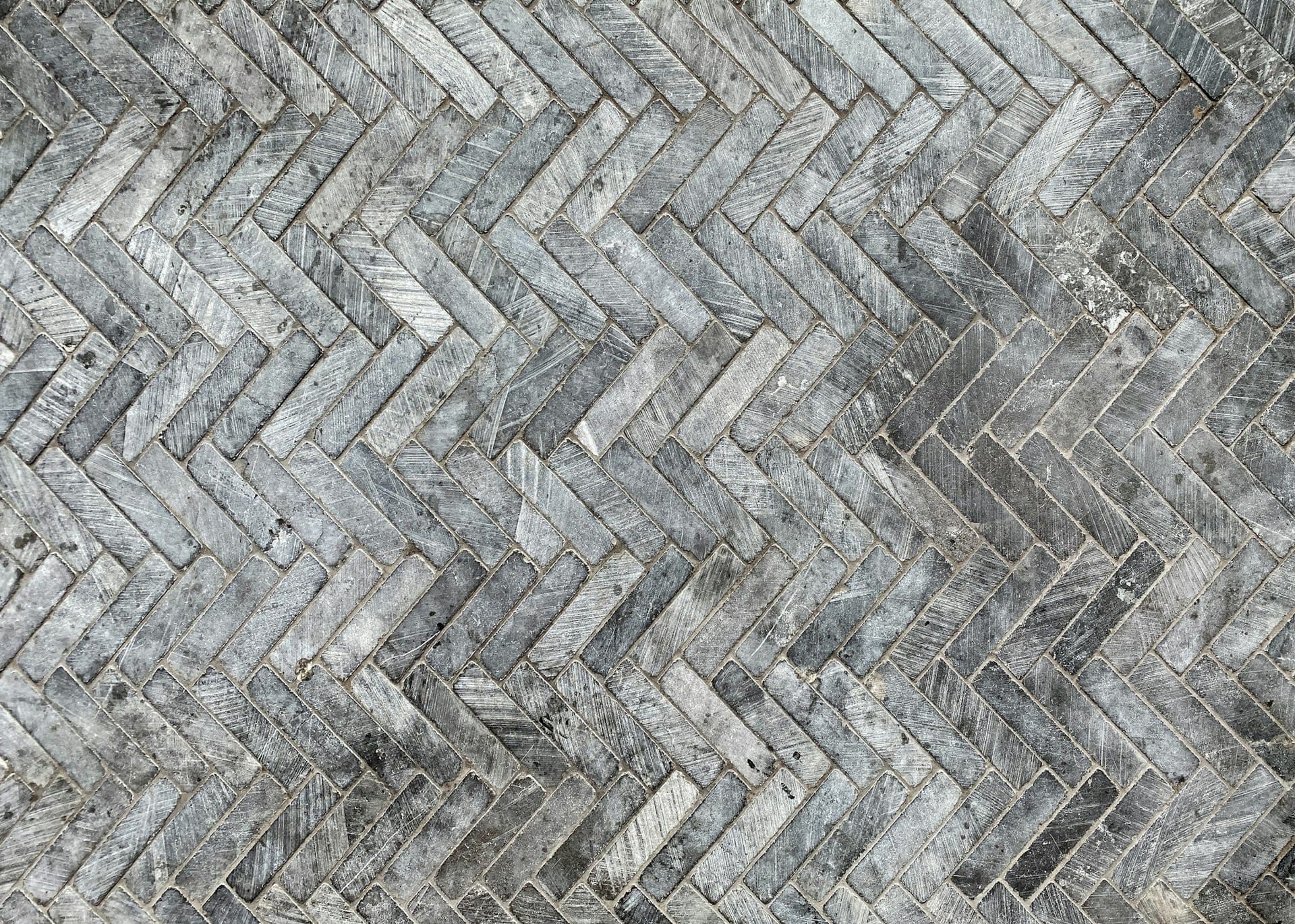 Gray marble mosaic tiles laid in a herringbone pattern