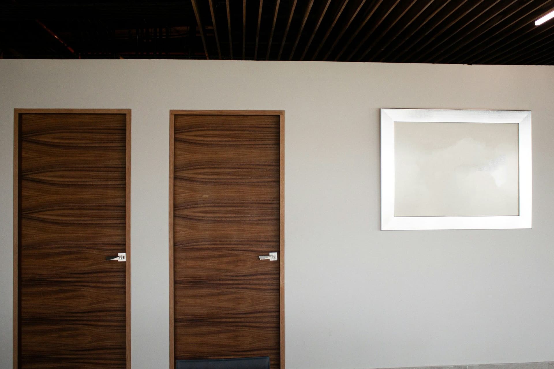 Two walnut-veneer interior doors side by side in a white corridor