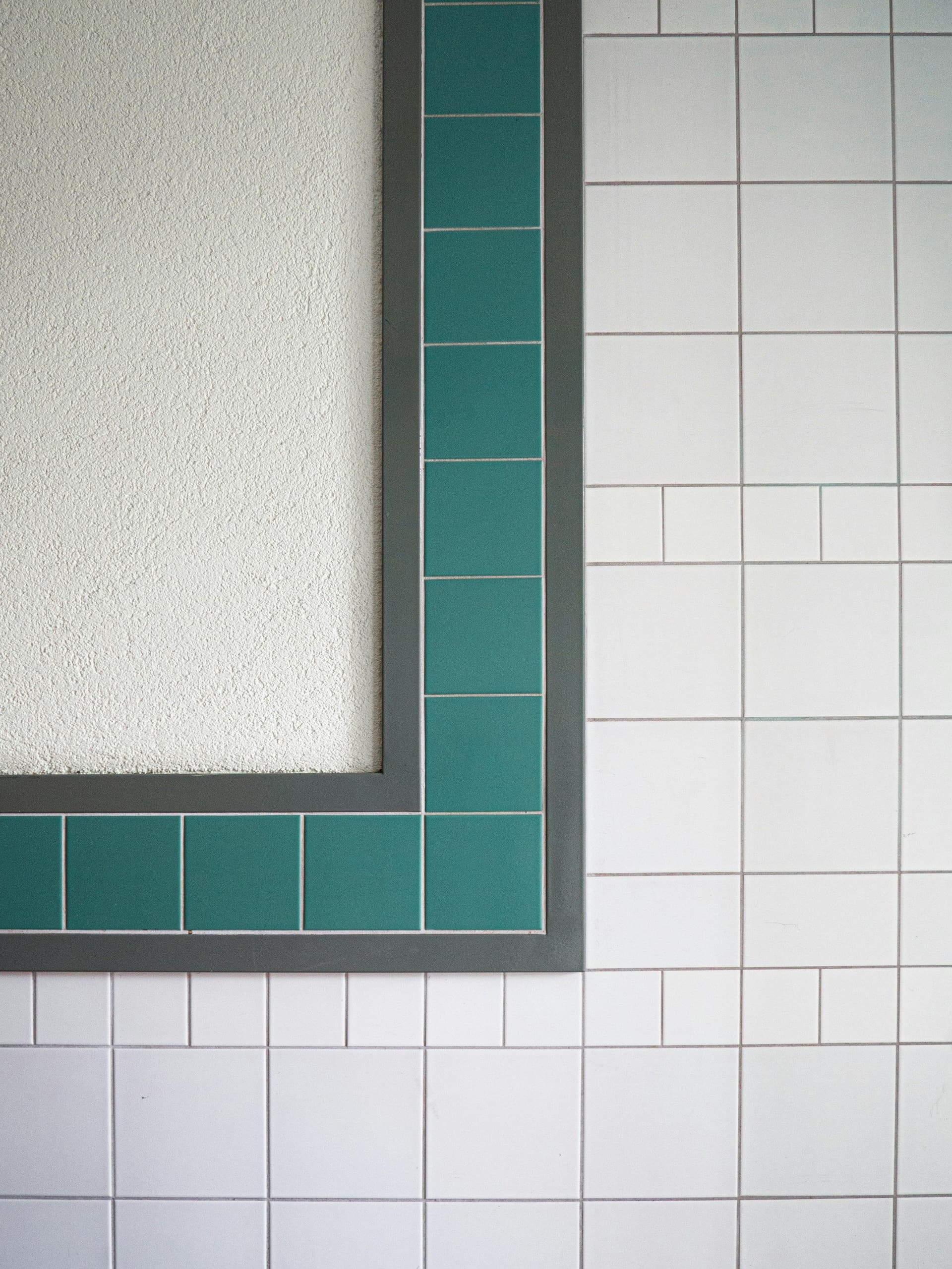 White wall tiles with a dark green tile border cut neatly around a recessed panel