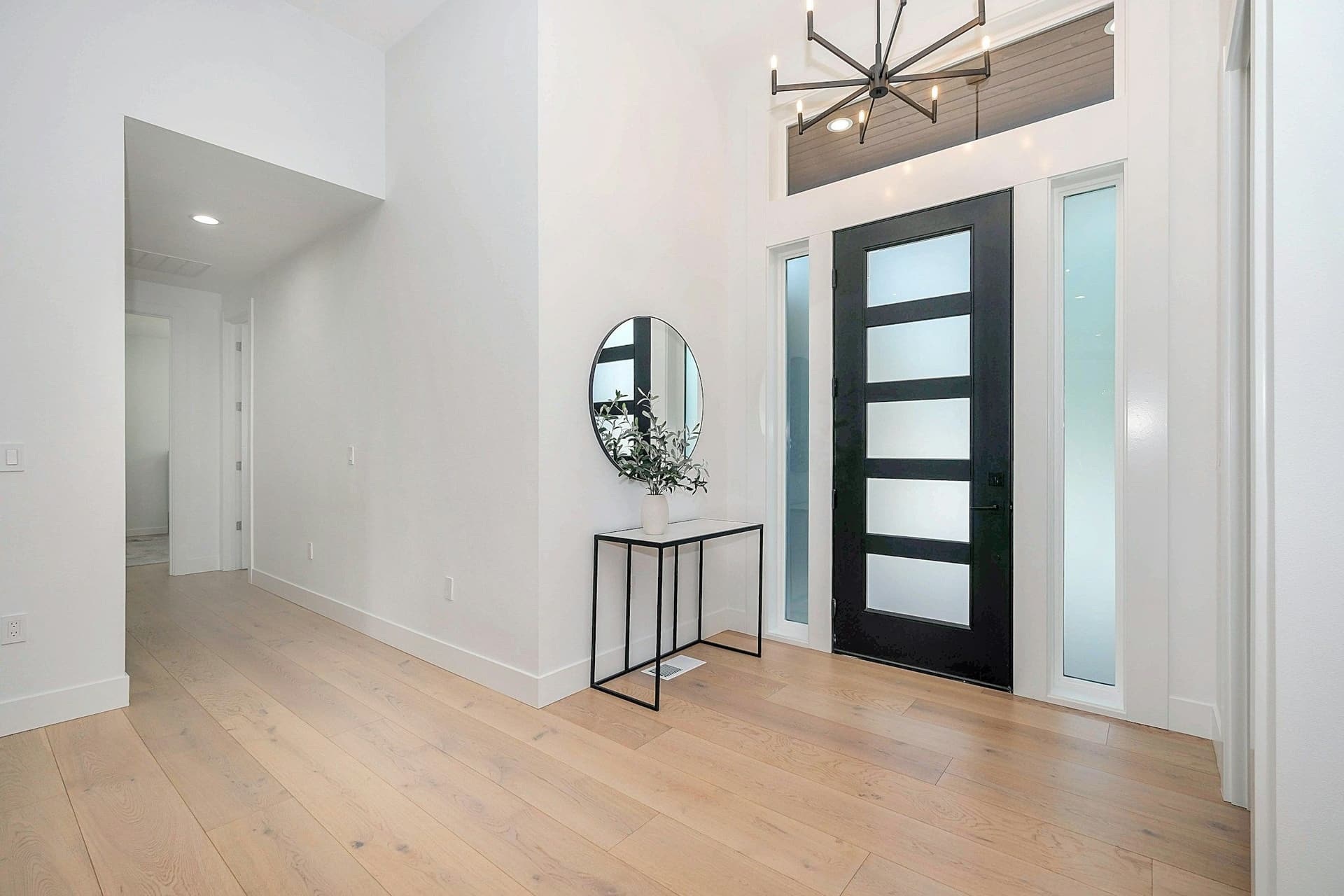 Entry hall with a black glass-panel front door, frosted side windows and a light wood floor