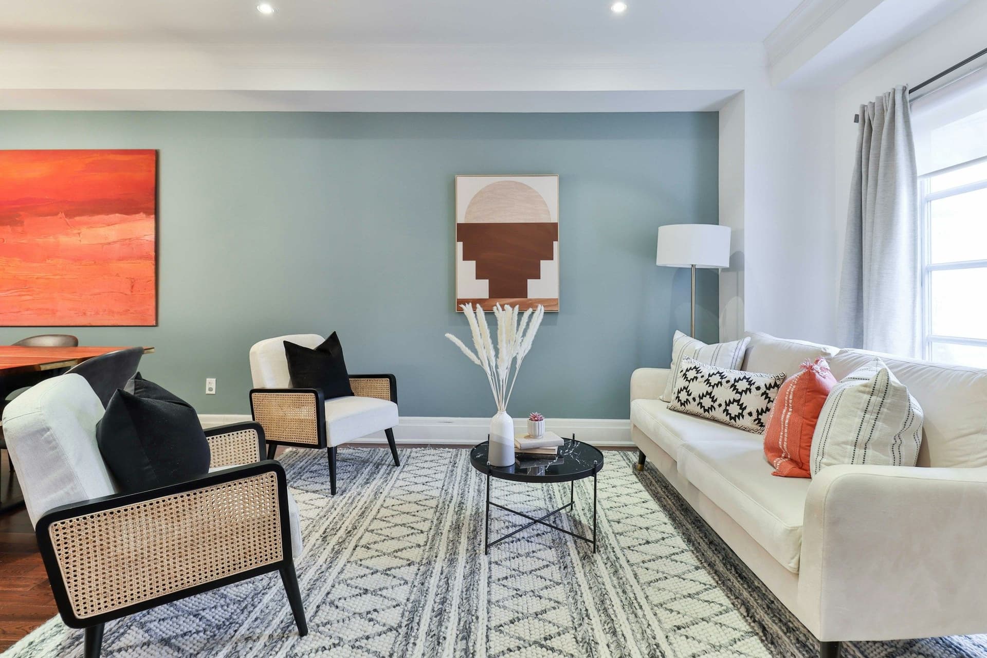 Living room with soft blue-gray walls, a white sofa, a patterned rug and abstract art