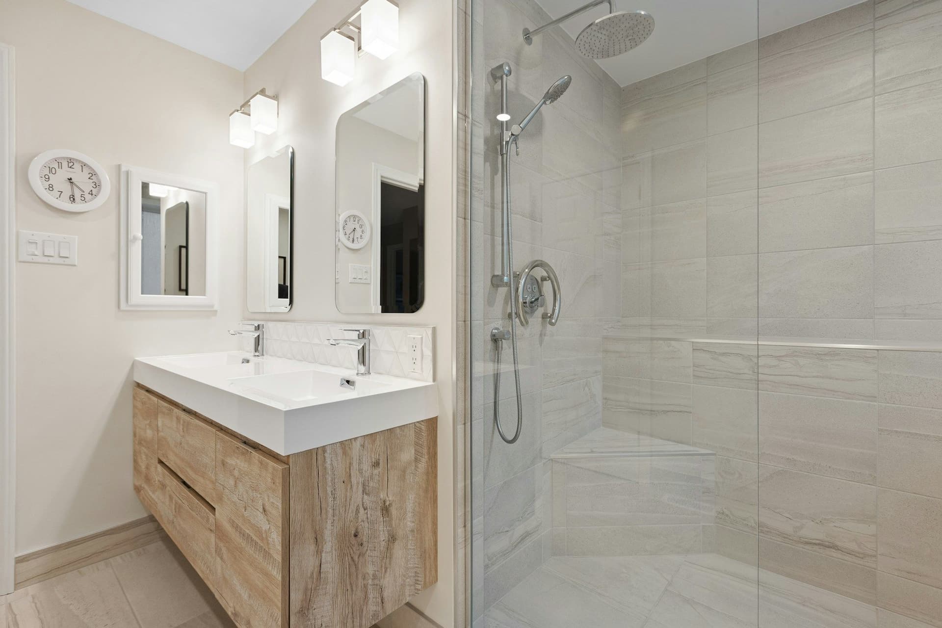 Bathroom with a floating vanity beside a walk-in shower with glass screen, hand shower and a built-in corner seat