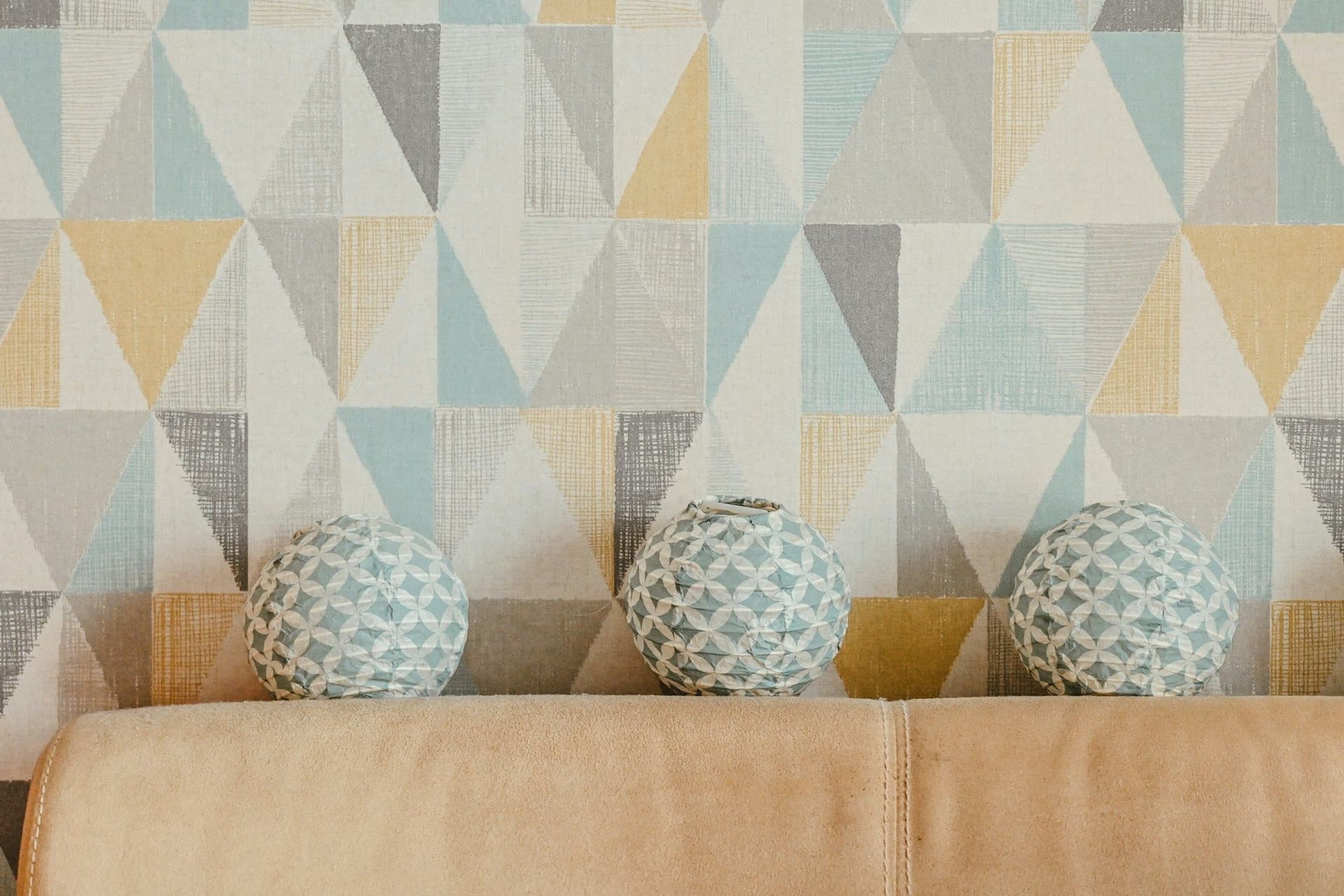 Pastel geometric wallpaper behind a sofa with three round patterned cushions