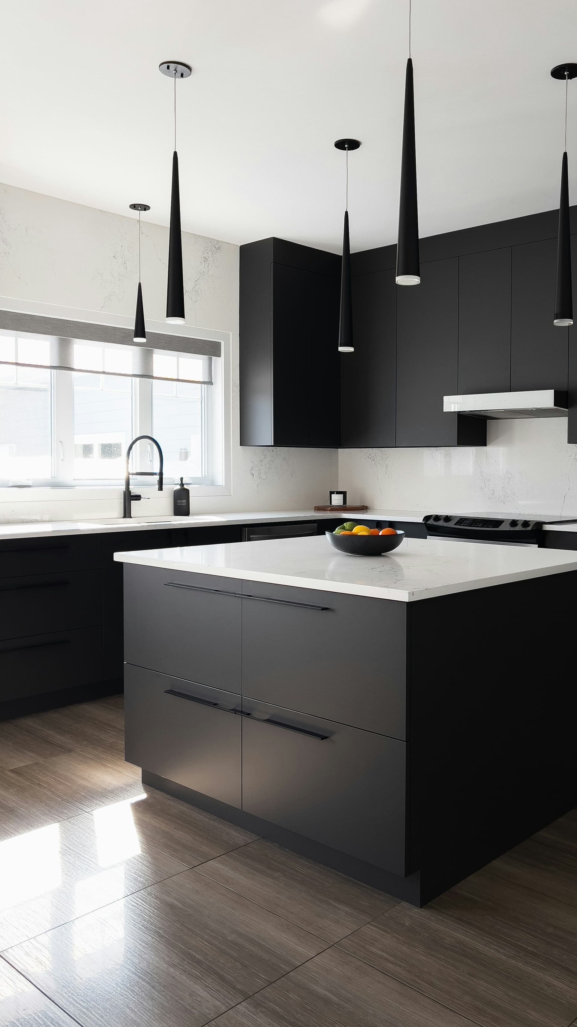 Kitchen with matte black cabinets, a white countertop island and slim black pendant lights