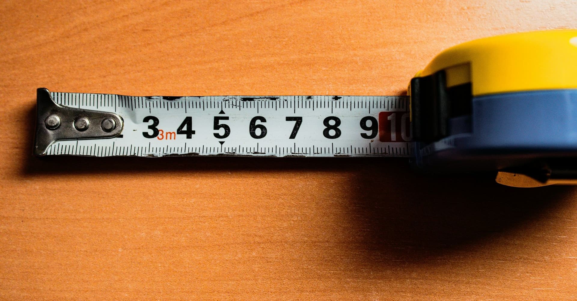 A yellow tape measure extended across a wooden surface