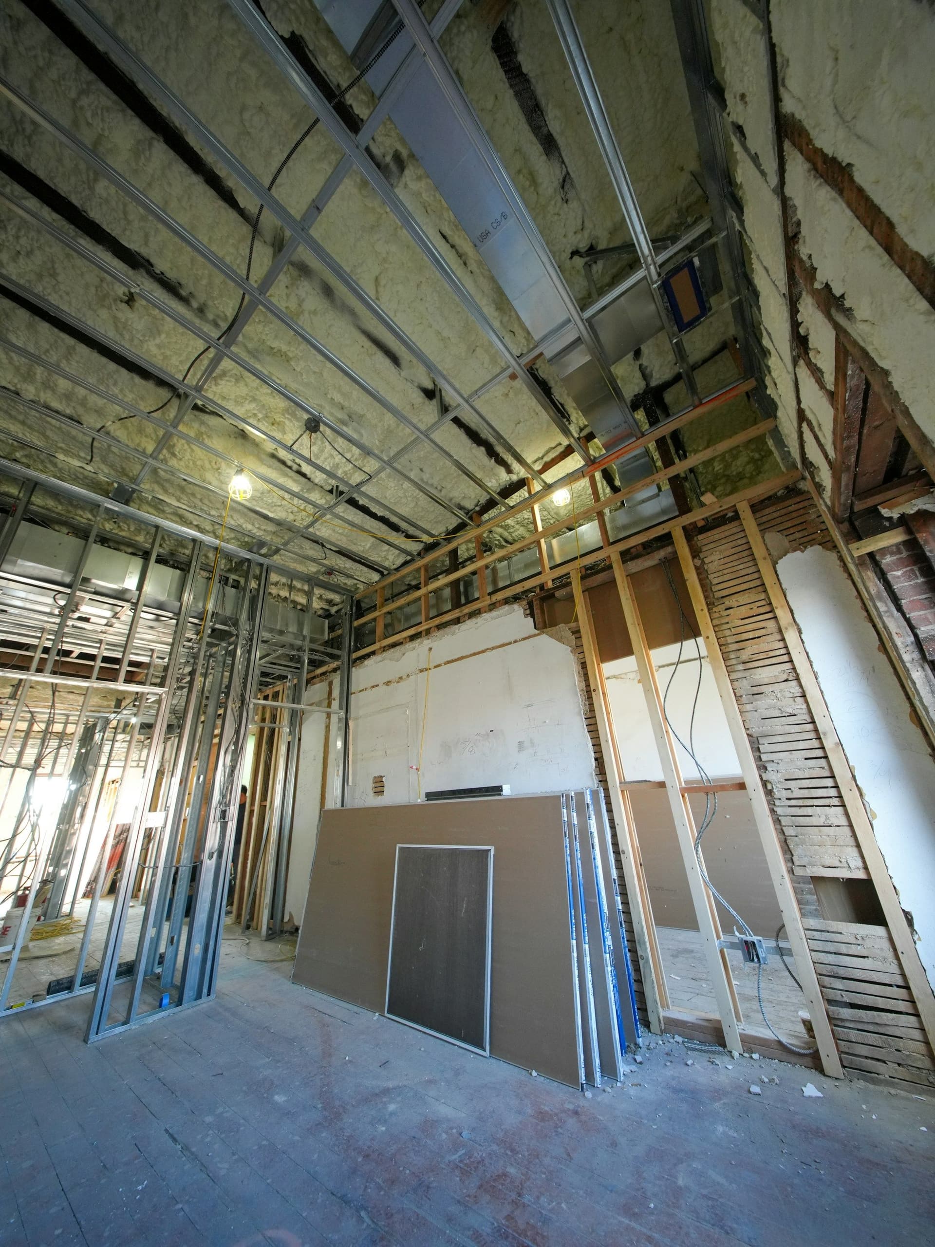 Metal stud framing with drywall sheets leaning against it in a room being divided into new spaces