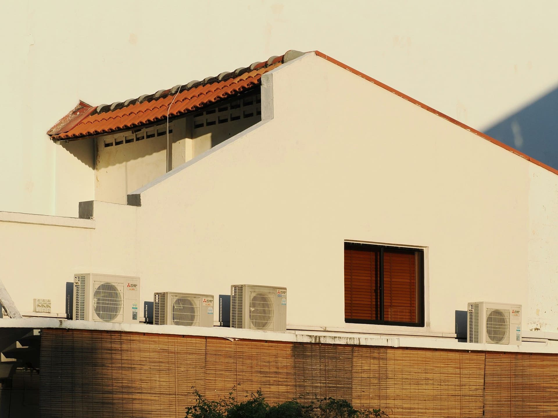 Outdoor AC units lined up along the parapet of a white house