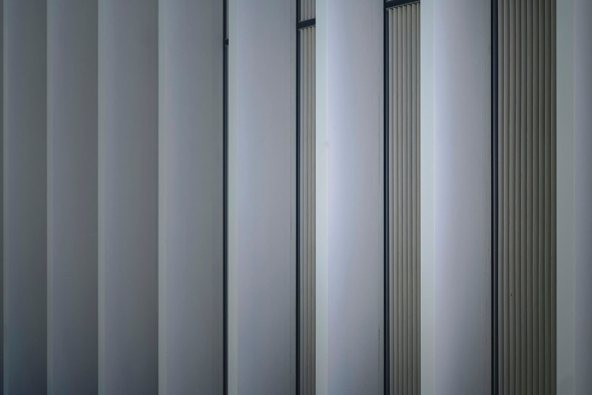 Vertical white cladding panels with thin dark gaps between them on a building facade